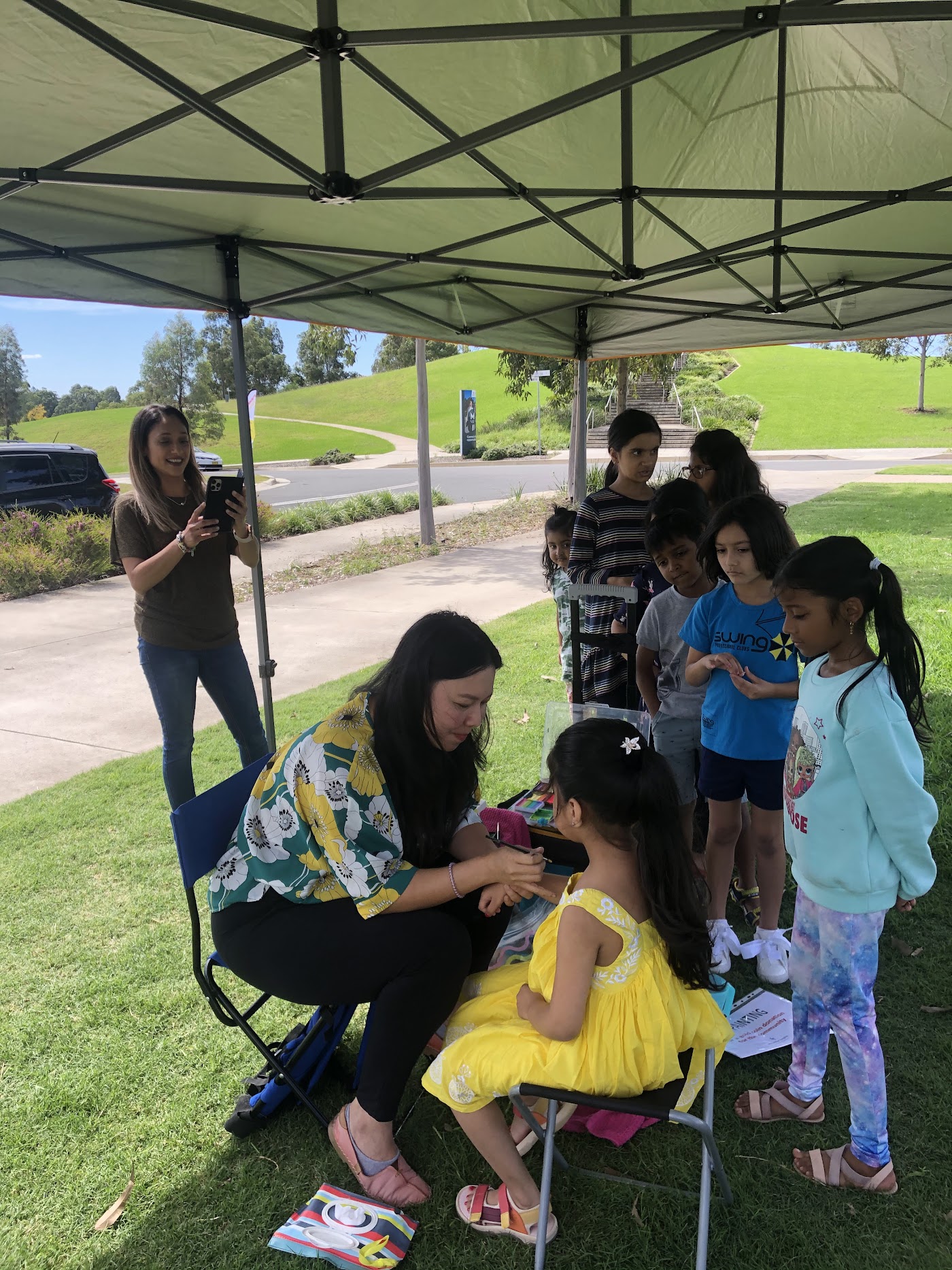 Children and parents sitting under a gazebo at the community event