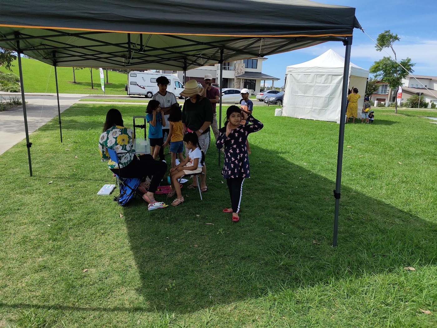Families seated under a marquee at the community barbecue